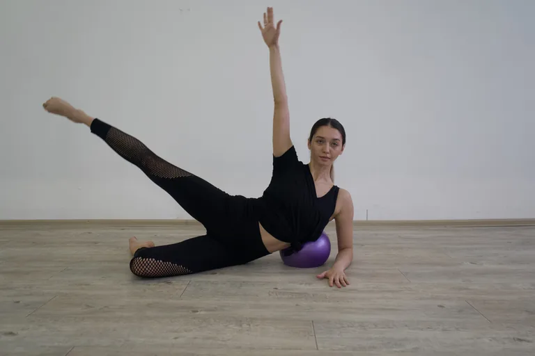 Una participante realiza un ejercicio de apoyo lateral con una pelota morada.