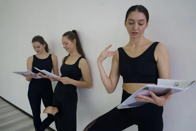 Three participants review printed workbooks together in a studio.